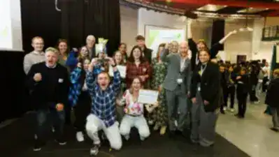 Groep jongeren en volwassenen vieren succes op de beurs in Luxemburg.